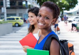 Lachende afrikanische Studentin mit Freundin in der Stadt